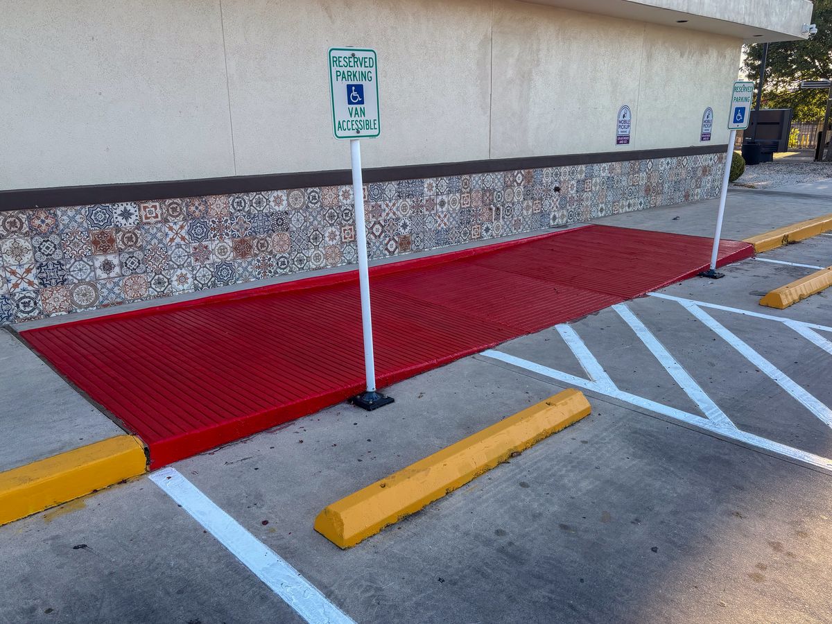 ADA accessible ramp with reserved parking signs and yellow wheel stops