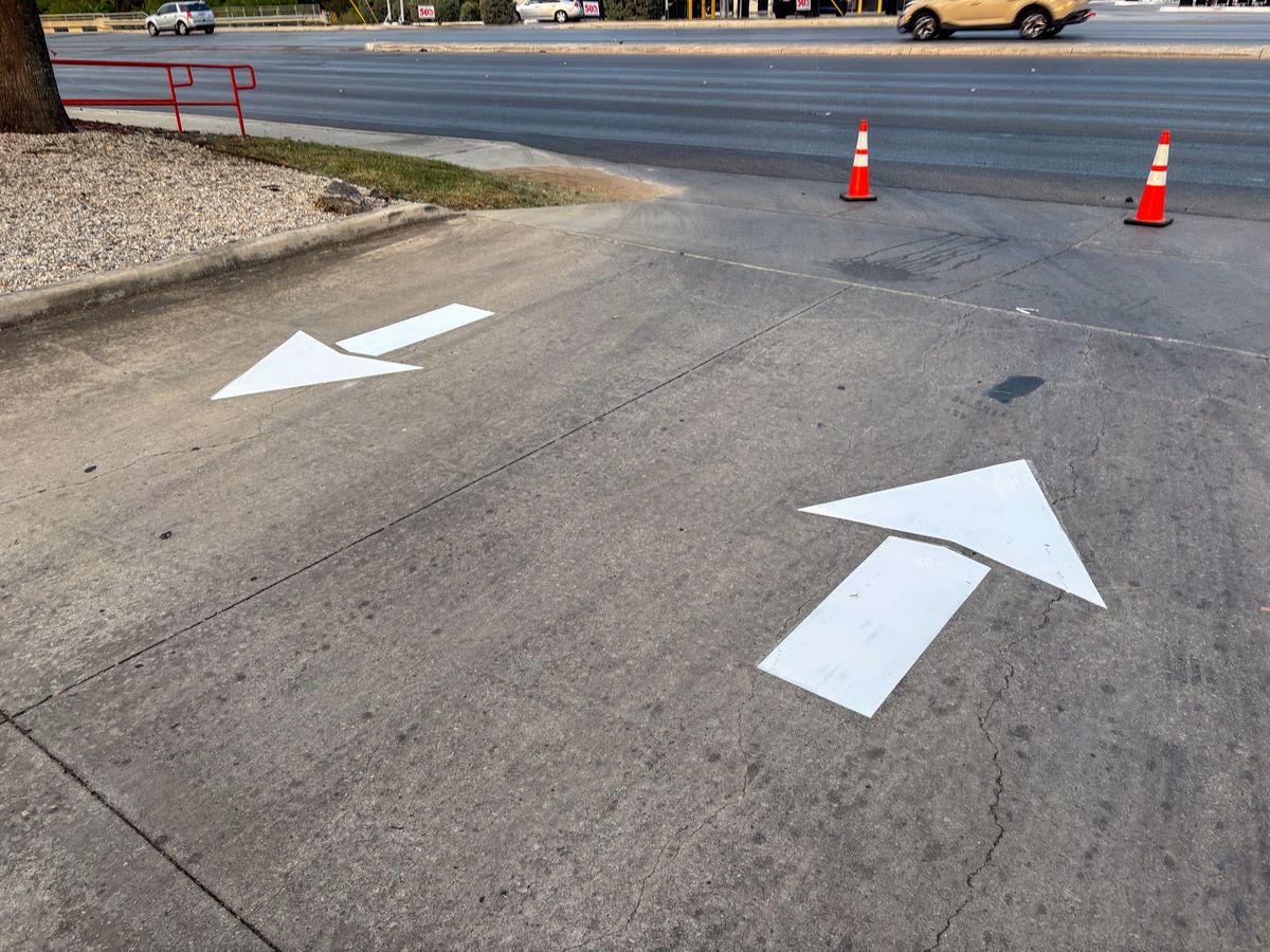 White directional arrows painted on parking lot pavement