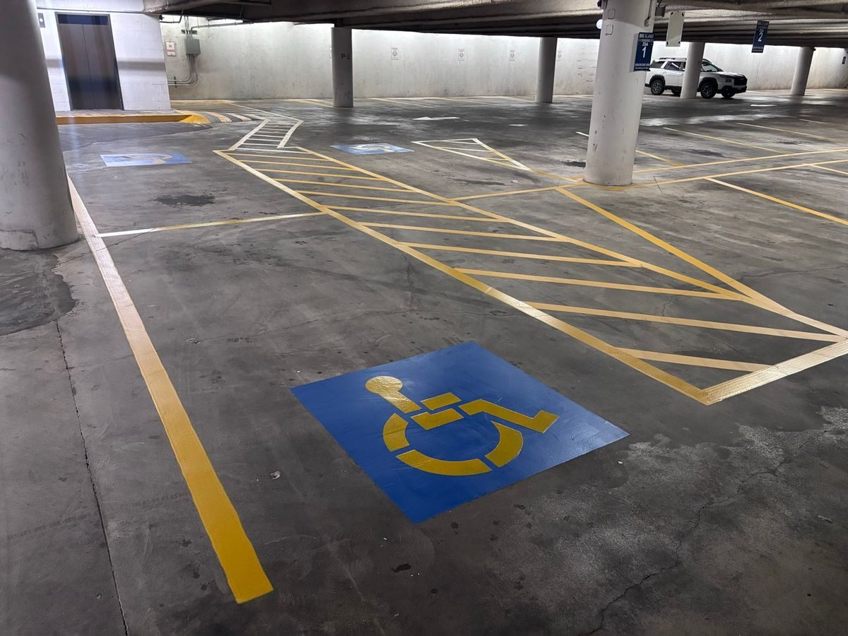 Accessible stall with a blue symbol beside a yellow crosshatched walkway in a covered parking garage