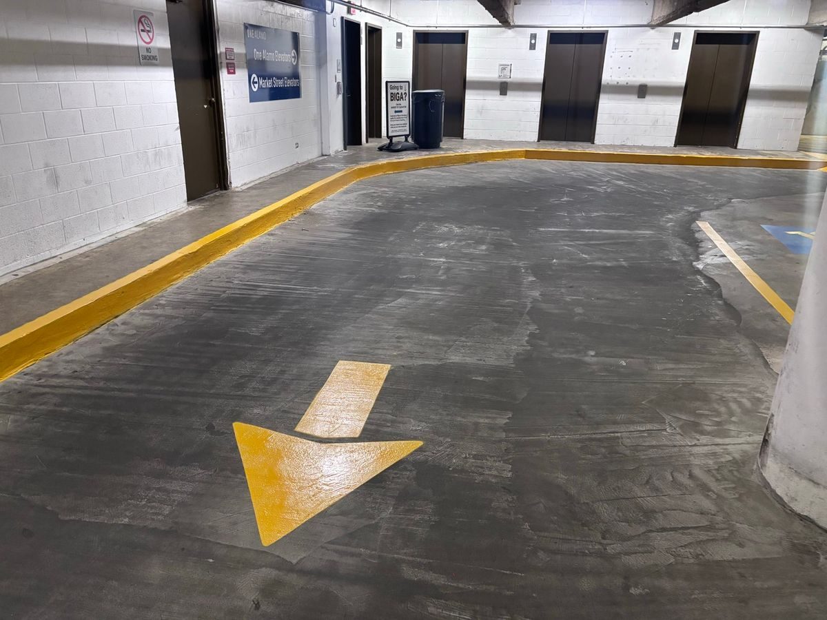 Yellow directional arrow painted on a parking garage floor