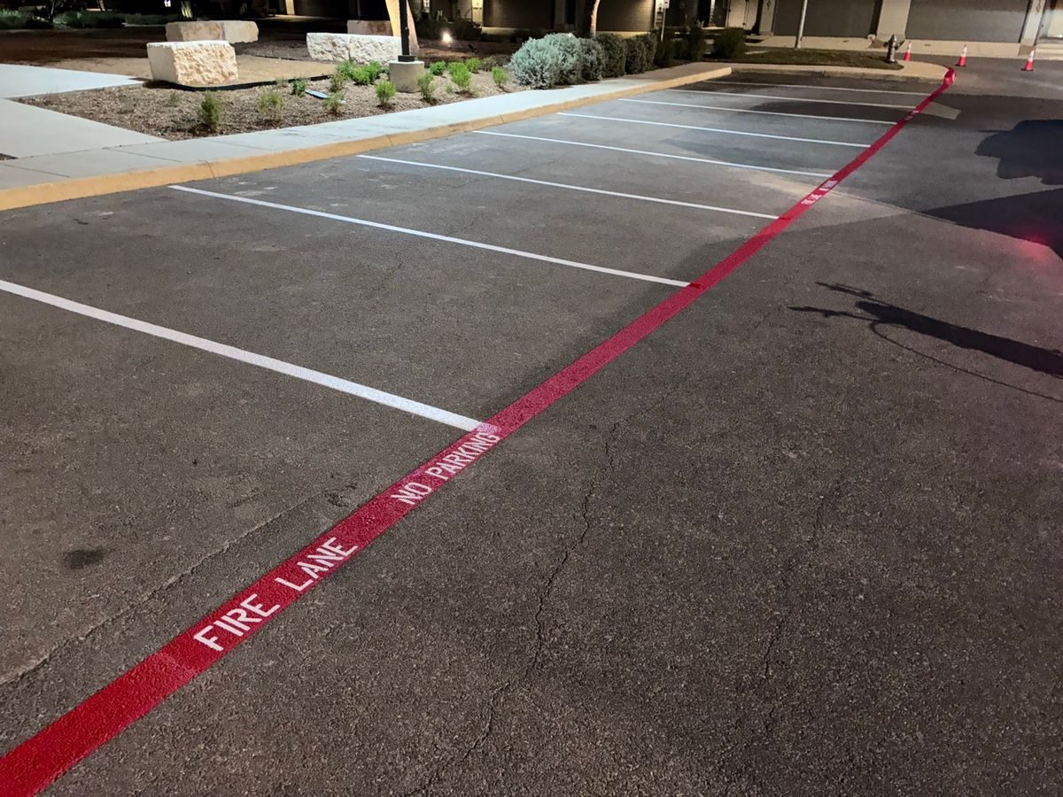 FIRE LANE stencil on a red pavement stripe beside parking stalls