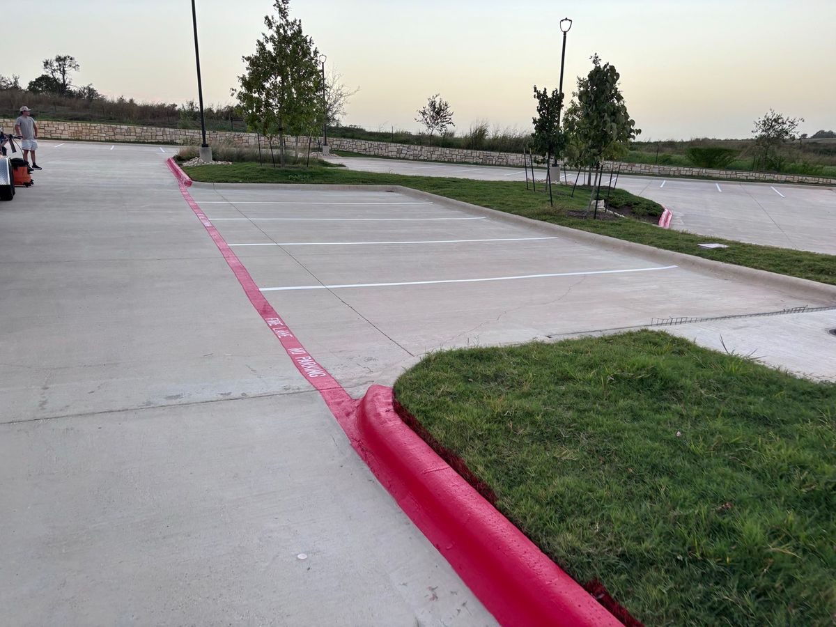New white stall lines beside a red fire lane curb on a concrete lot