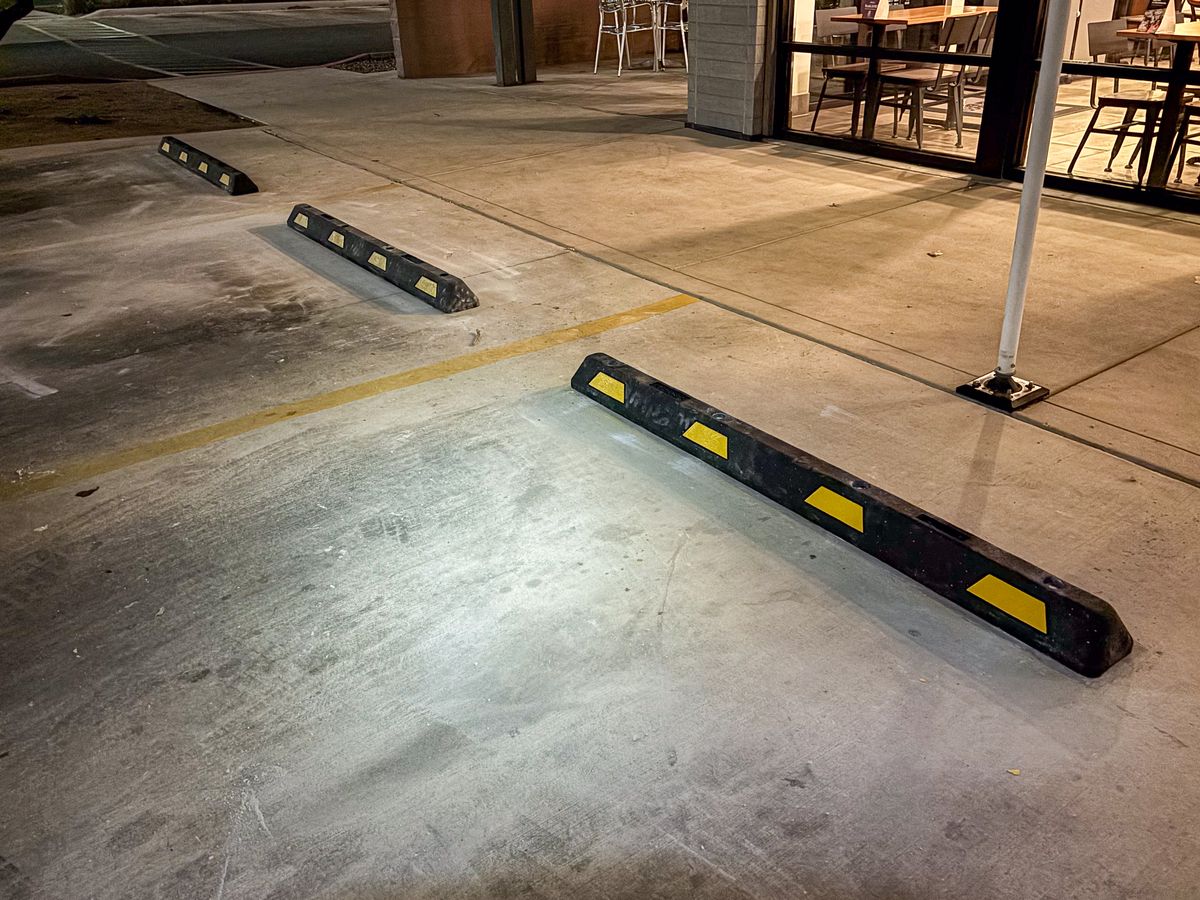 Black rubber wheel stops with yellow reflective strips