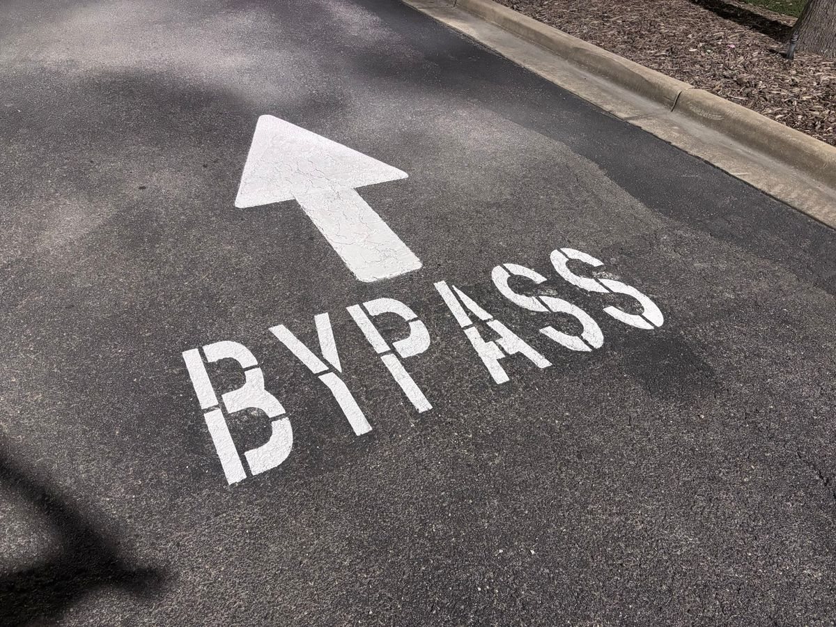 BYPASS stencil and arrow painted on asphalt