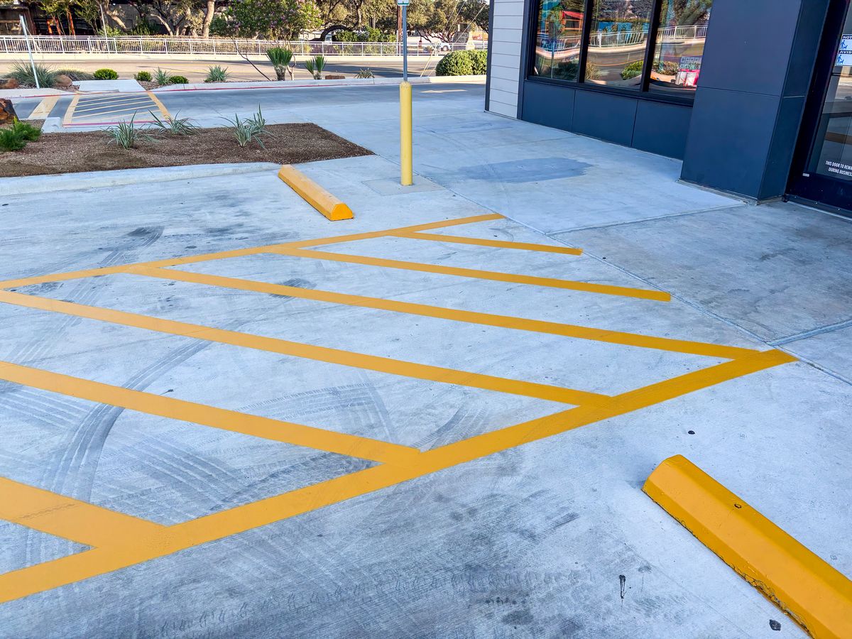 Yellow access aisle hatching with wheel stops and bollard