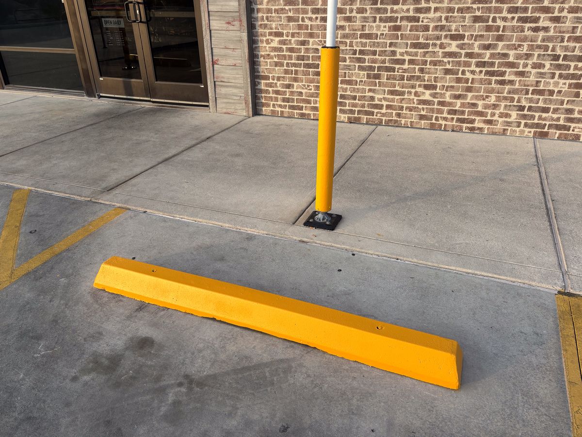 Yellow concrete wheel stop installed in a commercial parking lot
