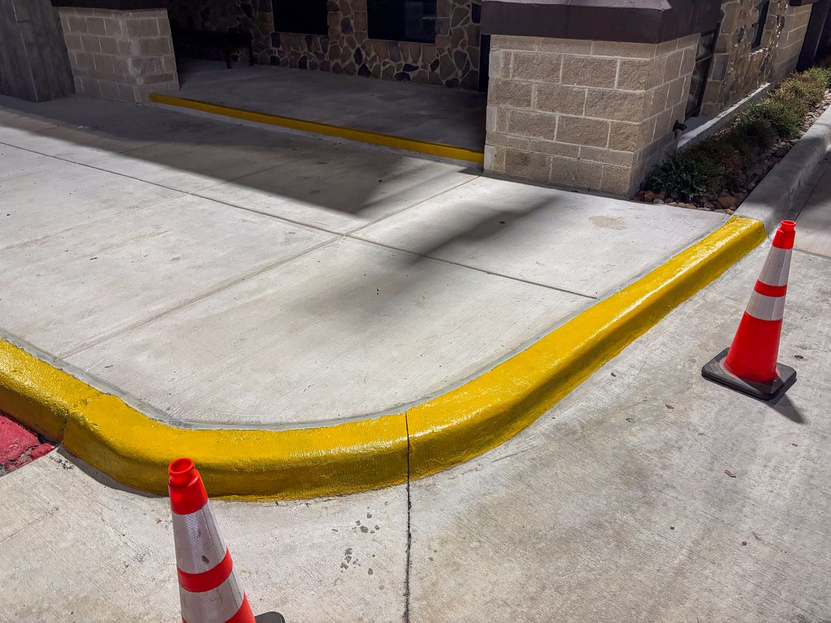 Fresh yellow curb painting with traffic cones